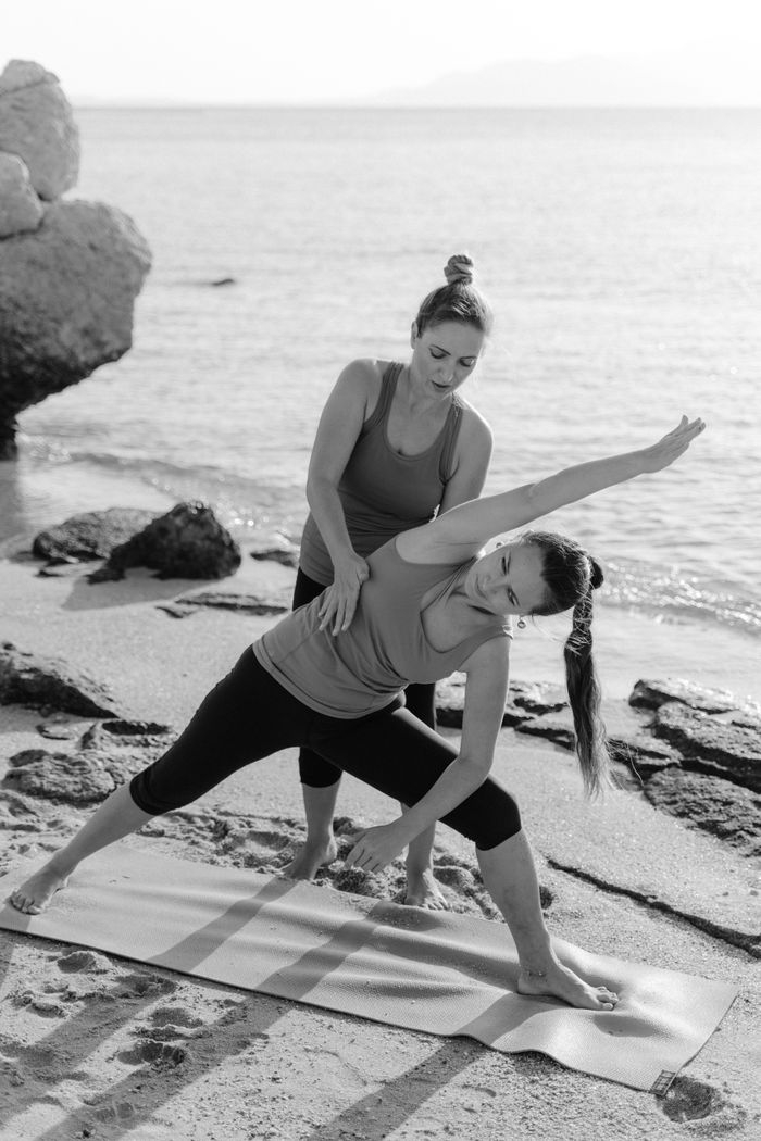 about-01 Black and white photo of women practicing yoga together on a beach. Ideal for fitness and wellness themes.